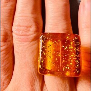 Lucite amber color w/ sparkles ring. Size 5 & 3/4